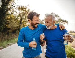  Two men walk side by side laughing. 